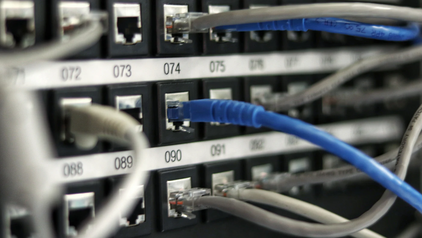 Kabel jaringan biru dan abu-abu tertancap pada panel patch
