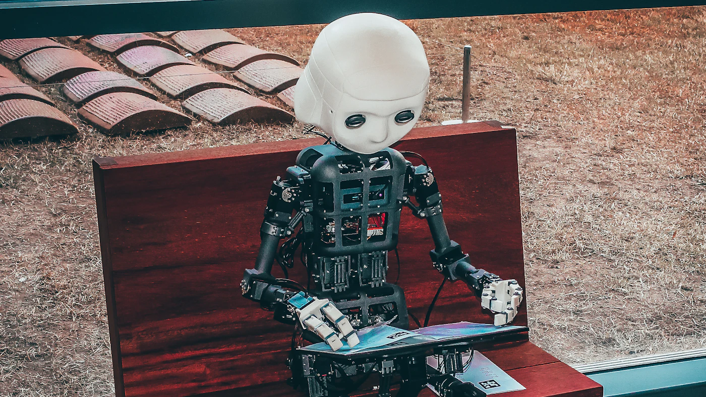 Robot humanoid duduk sambil memegang bahan bacaan