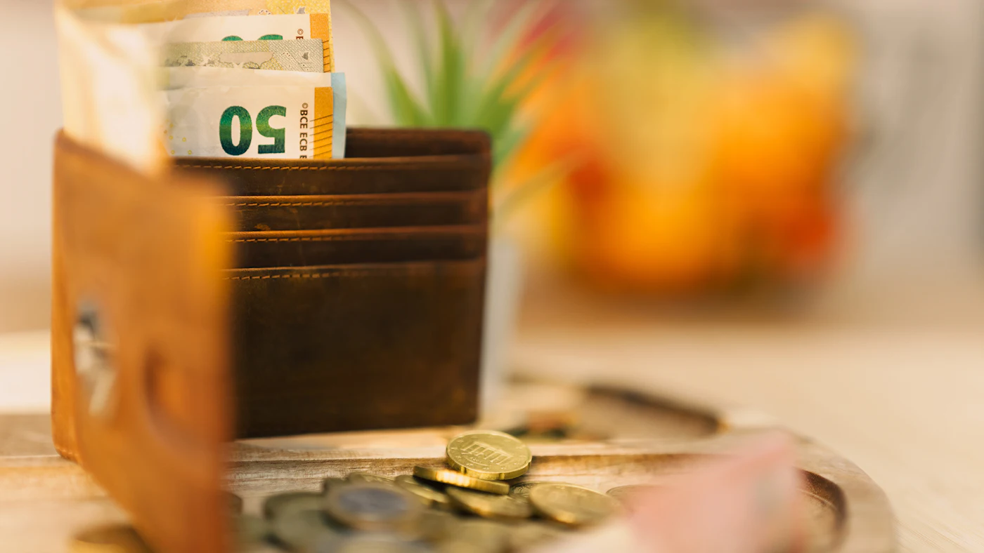 A wallet on a table full of cash